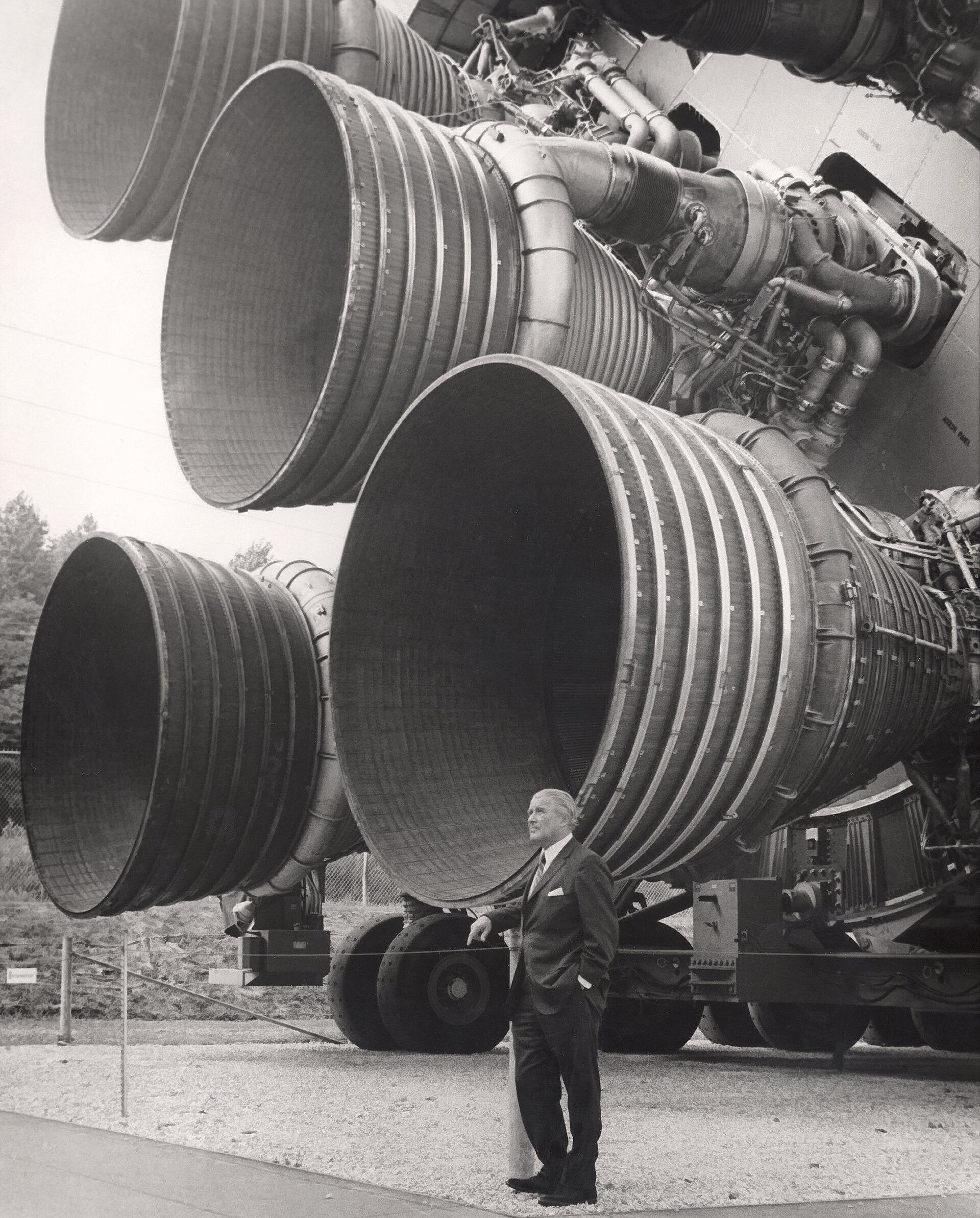 Wernher von Braun standing in front of Saturn V S-IC first-stage engines.